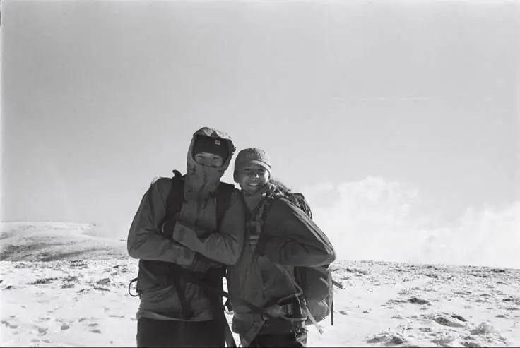 Two friends in winter gear on a snowy summit